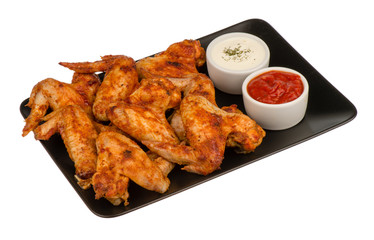 Roasted chicken wings on the black plate isolated.