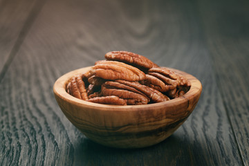 pecan nuts in olive wood bowl on oak table