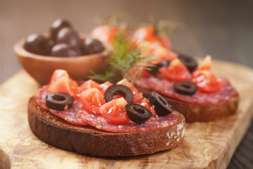rye sandwich with salami and tomatoes on wood table