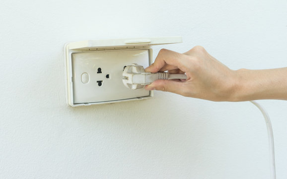 Female hand plugging in appliance to electrical outlet in wall o