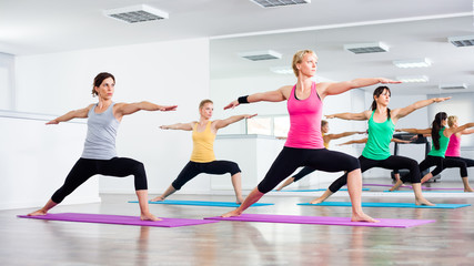 Four girls practicing yoga, Virabhadrasana / Warrior pose