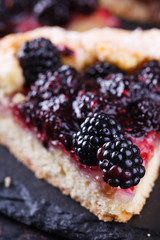 Galette with blackberries on a black background.selective focus