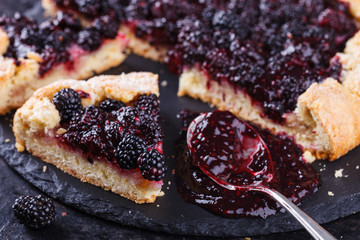 Galette with blackberries on a black background.selective focus
