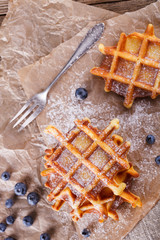 Belgian waffles with blueberries sprinkled with powdered sugar, closeup. selective focus