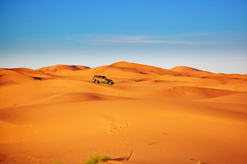 Fototapeta na wymiar Jeep in sand dunes in the Sahara Desert, Morocco