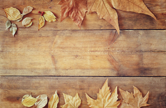 top view image of autumn leaves over wooden textured background