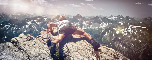 Man Scrambling Over Rocks on Mountain Ledge