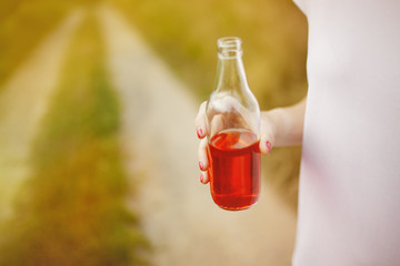 Young beautifil woman holding in her hand red softdrink. Countryside road