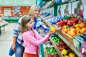 Mother and daughter chooses bell peppers in supermarket