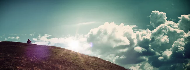 Foto auf Acrylglas Natur Einsame Person, die auf einem Hügel sitzt und den Sonnenaufgang beobachtet