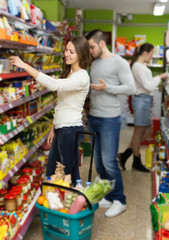  customers standing near shelves with canned goods at shop
