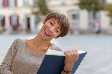 Young woman sitting reading a book outdoors