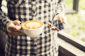 Hipster girl with cappuccino and smartphone