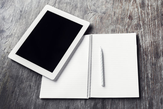 Digital tablet with blank diary and pencil on a wooden table