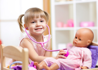child playing doctor role game examinating her doll using