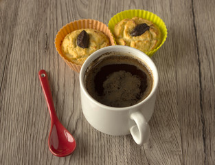 Coffee cup and two cupcakes on the wood background