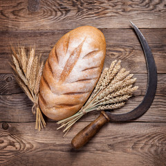 Bread, ears and sickle on old boards