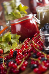 Berries jam in glass jar and wood background