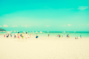 Fototapeta na wymiar Blurred people on white sand beach with blue sea an sky background