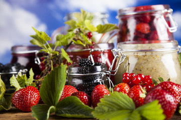 Berries jam in glass jar and wood background
