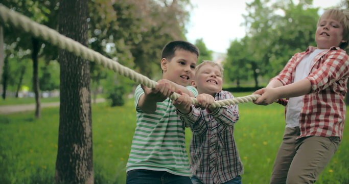 Three little boys taking part in tug of war competition 
