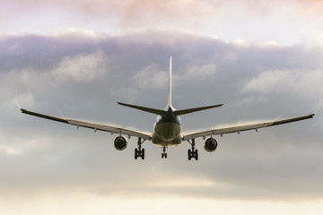 Plane is flying to the runway. Nice colorful cloudy background.