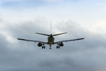 Fototapeta na wymiar Small airplane is flying to the runway. Nice cloudy background.