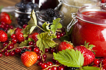 Jams in glass jars with wood and fresh berries 