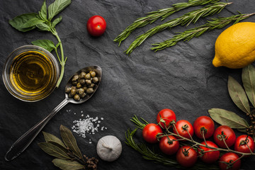 Herbs mix with tomatoes, lemon and olive oil on the black stone table