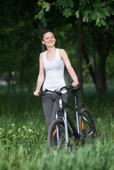 Naklejka premium Girl on a bicycle in a forest