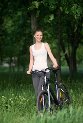 Naklejka premium Girl on a bicycle in a forest