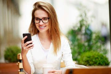 Girl texting on the smart phone in a restaurant terrace with an