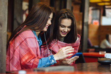 Two girl sitting listening to music with a smartphone