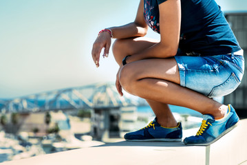 Young woman in blue jeans and sneakers is looking down the bridge - 90828678