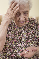ill senior woman holding pills on palm