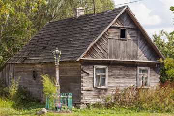 old house and cross in front of building in Aleksicze Poland