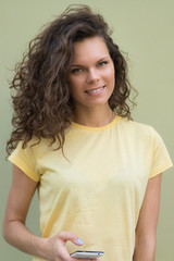 Pretty smiling young woman in a yellow t-shirt holding a cell ph