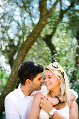 Young happy beautiful wedding couple in white dresses is hugging kissing in the park in summer - 90830671