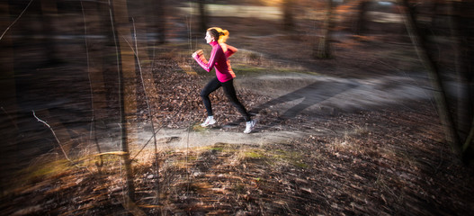 Young woman running outdoors in a city park on a cold fall