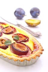 tart of pastry with plums on a white background