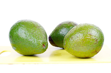 Three avocado on yellow board