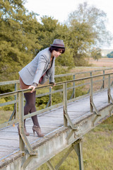 Fashionable young woman on a rustic footbridge