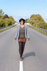 Stylish modern young woman walking along a road