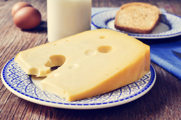 cheese, milk, eggs and bread on a rustic wooden table, with a fi