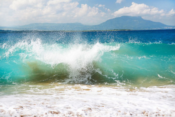 Surfing sea waves with foam on white tropical sandy beach
