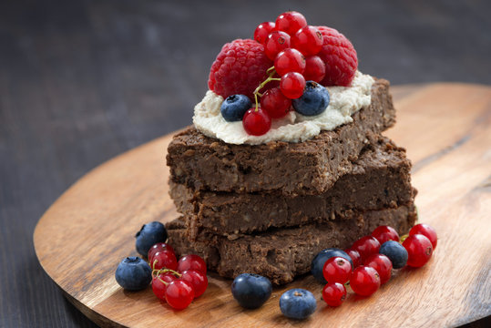 chocolate brownie cake with nuts and berries on wooden board