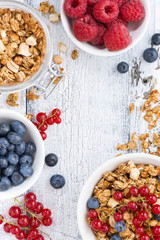 granola and fresh berries on white wooden background