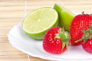 Strawberries and limes on white plate
