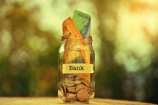 Saving Money Concept With Bank Text Written On Glass Jar.Selective Focus And Shallow Depth Of Field.