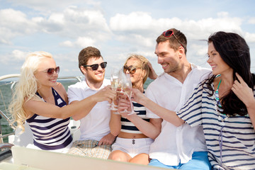 smiling friends with glasses of champagne on yacht